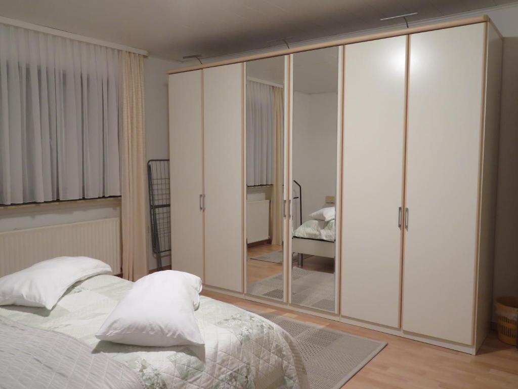 a bedroom with a large white closet with mirrored doors at Zum Herrenwald in Stadtallendorf