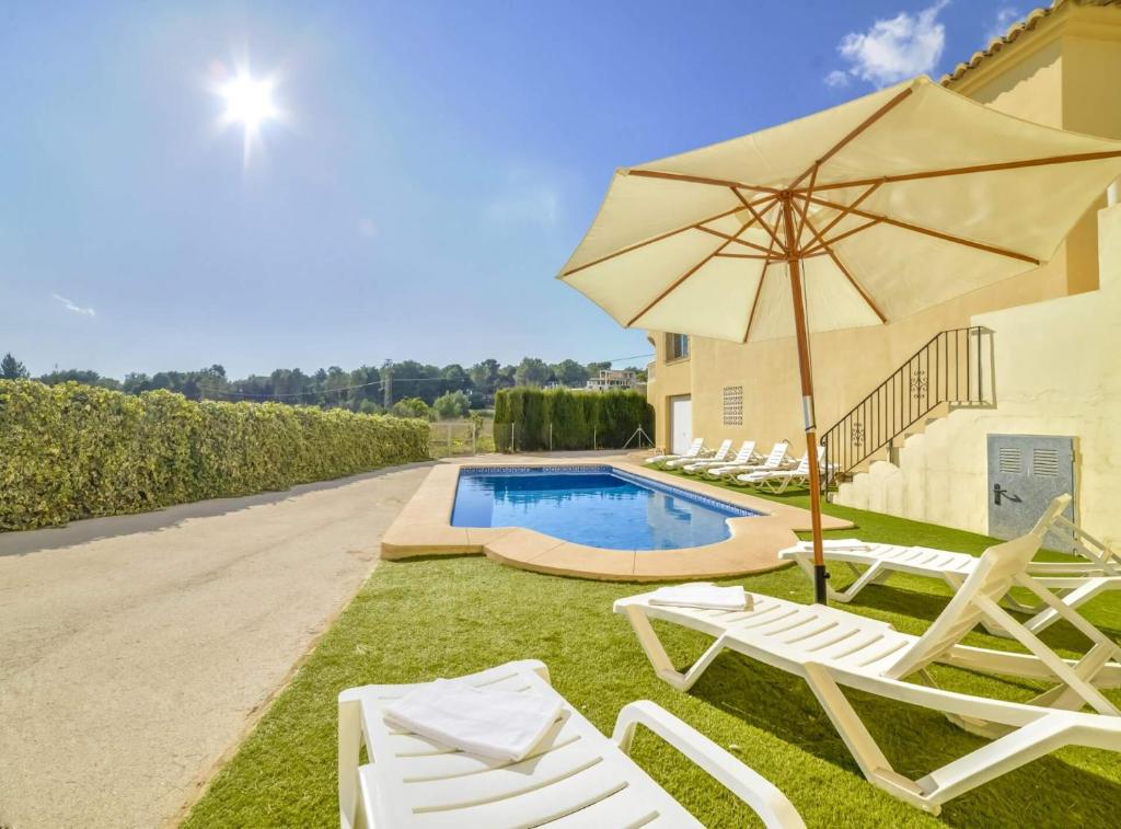 莫萊拉的住宿－Villa Haya - Plusholidays，一组草坪椅和一把伞,位于游泳池旁