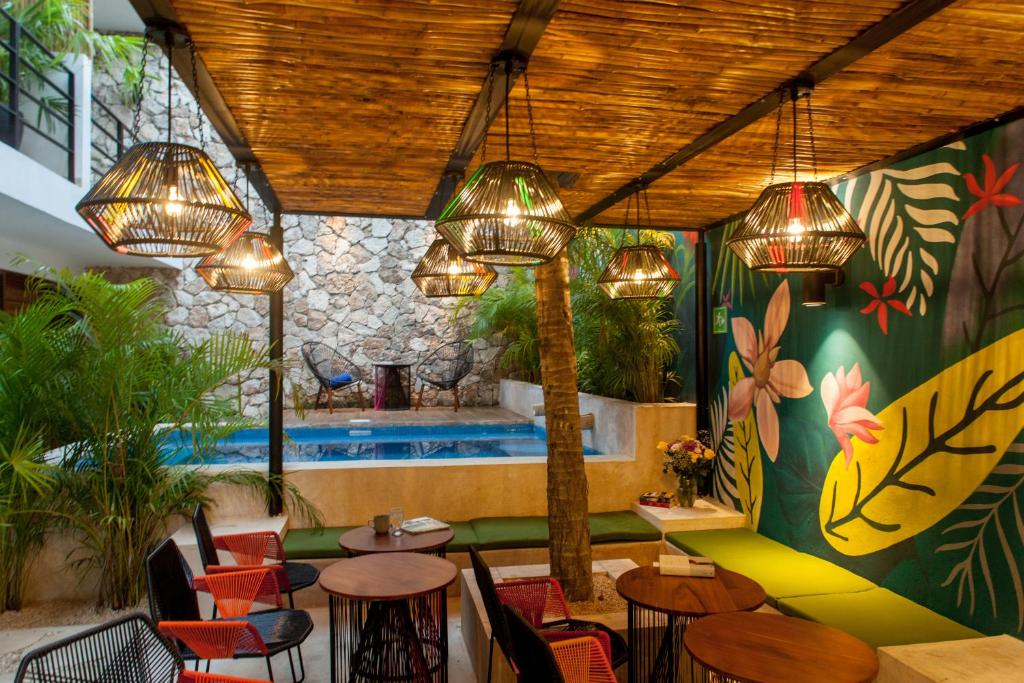 Un restaurante con mesas y sillas y una piscina. en Latino Hotel Boutique, en Tulum