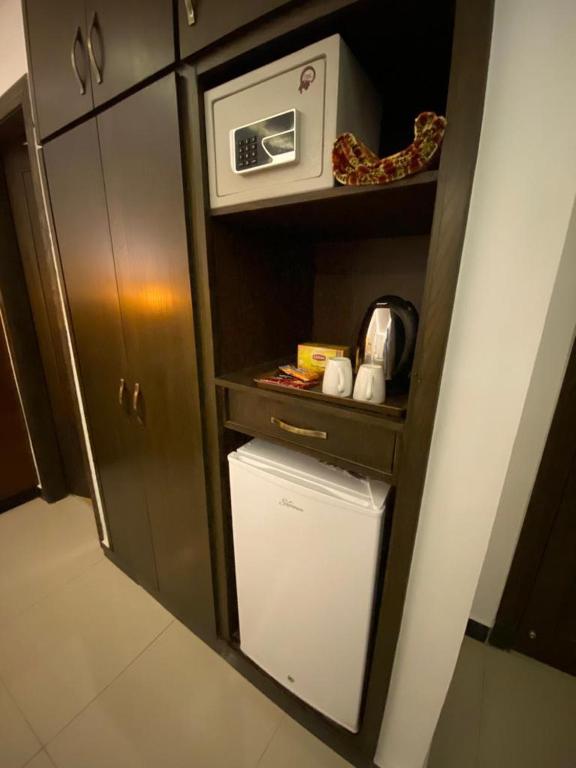 a small kitchen with a microwave and a refrigerator at Grand Mongolia Hotel in Rawalpindi