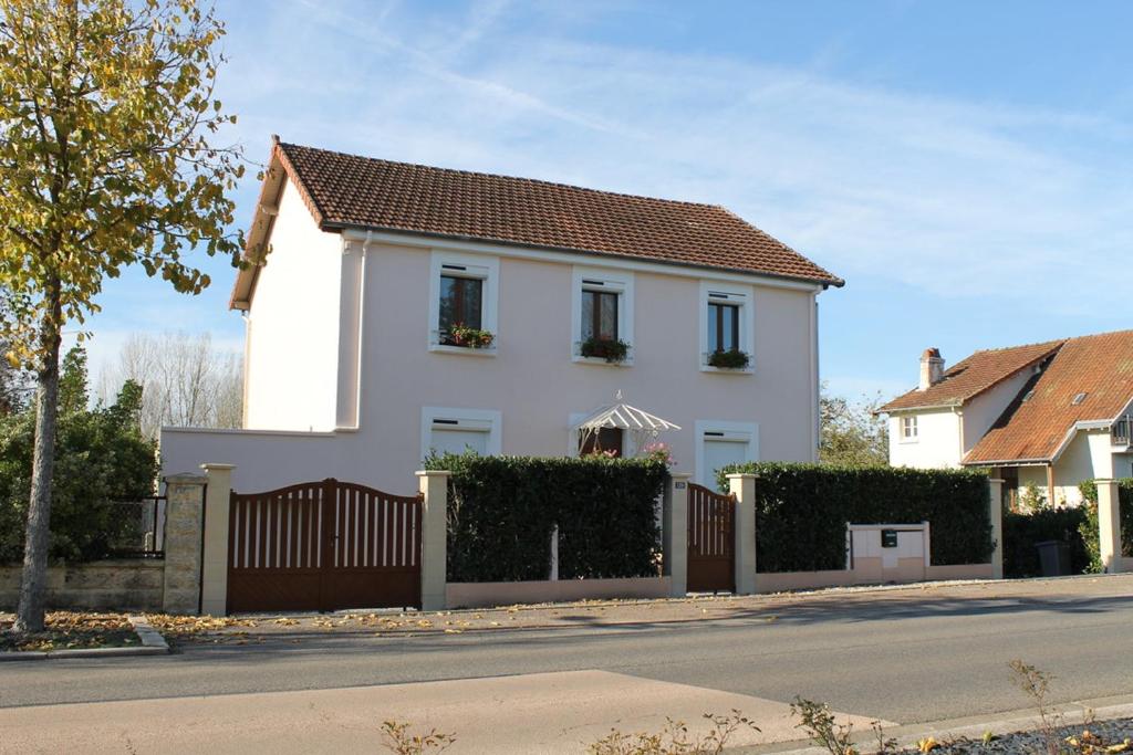 uma casa branca com uma cerca numa rua em Les Géraniums em Cosne Cours sur Loire