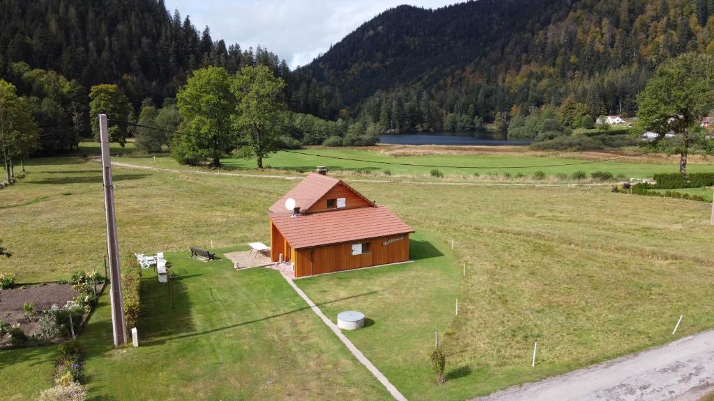 a small house in a field next to a lake at Chalet pour amoureux de la nature avec vue sur le lac de Retournemer in Xonrupt-Longemer