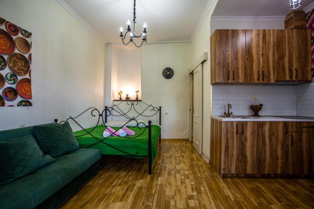ein Wohnzimmer mit einem grünen Sofa und einer Küche in der Unterkunft downtown apartment near Sulfur baths in Tbilisi City