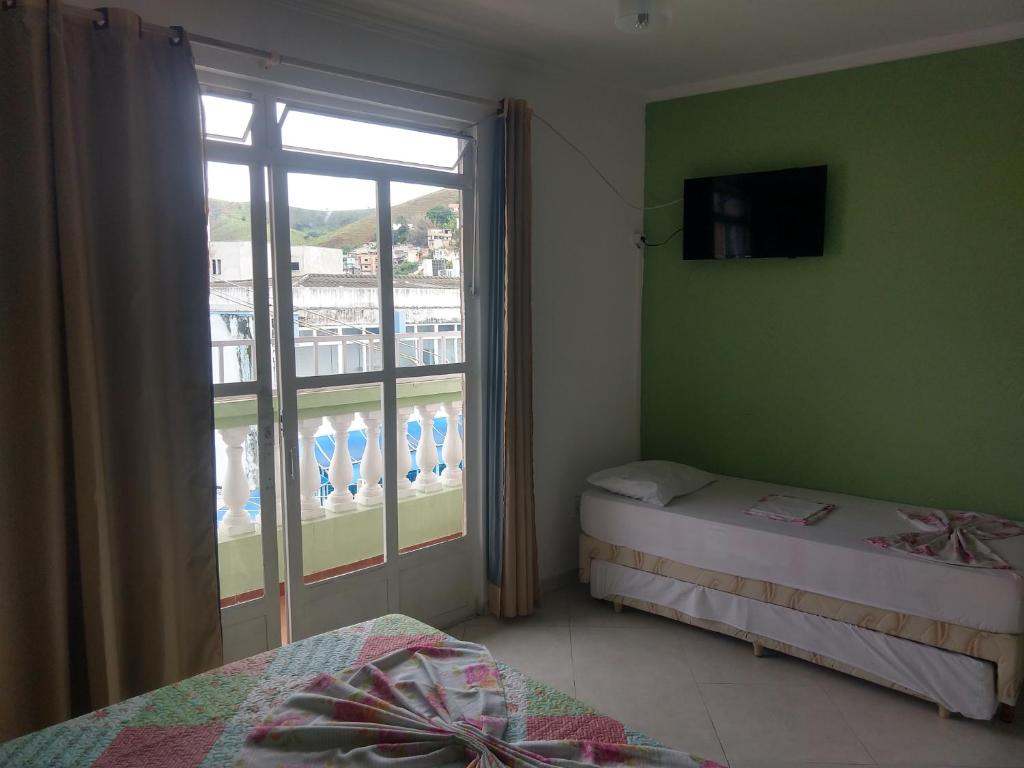 a bedroom with two beds and a window with a balcony at Pousada Coração de Jesus in Aparecida