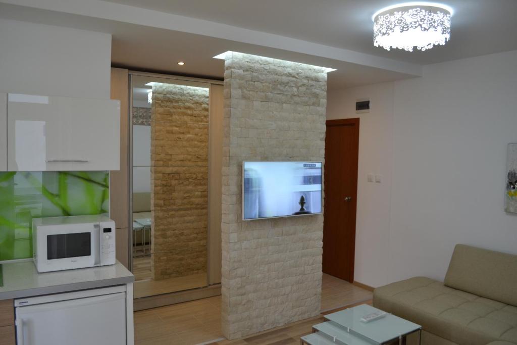a living room with a tv on a brick wall at Peevi Apartments Elit 1 in Sunny Beach