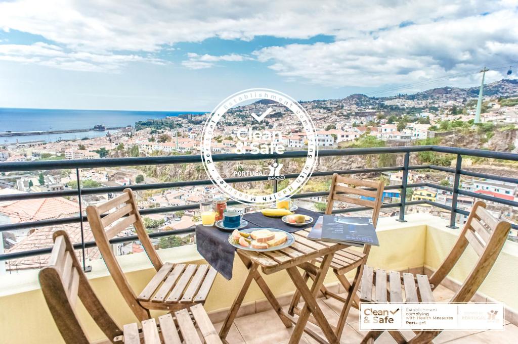 a table and chairs on a balcony with a view of the city at Trendy Apartments in Funchal