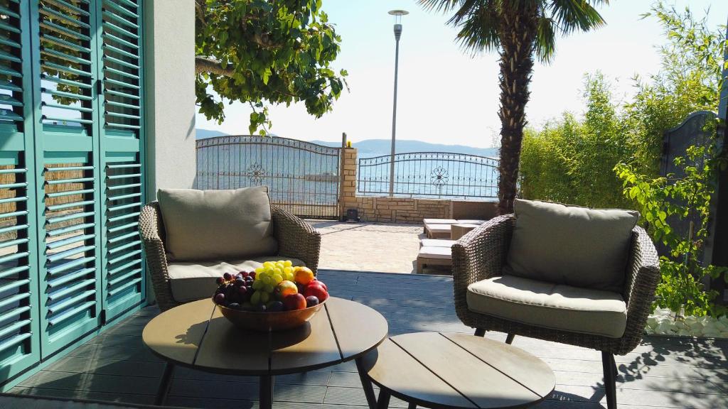 een patio met 2 stoelen en een fruitschaal op een tafel bij Beach House Ana in Sukošan