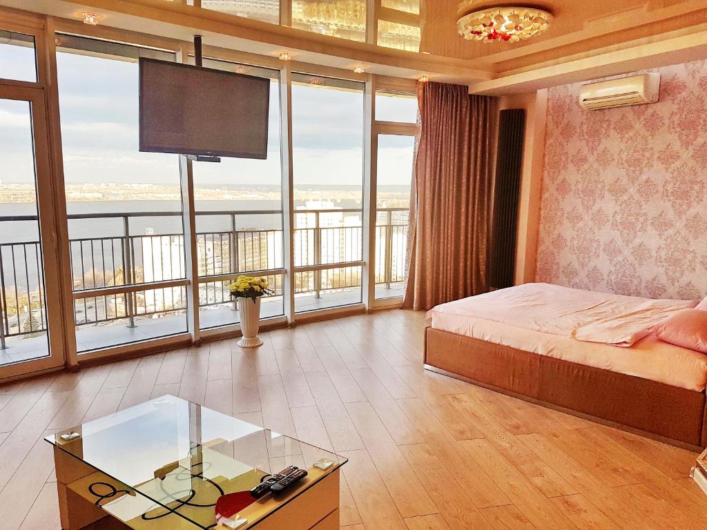 Schlafzimmer mit einem Bett, einem TV und Fenstern in der Unterkunft Best Apartments in Most City, River View in Dnipro