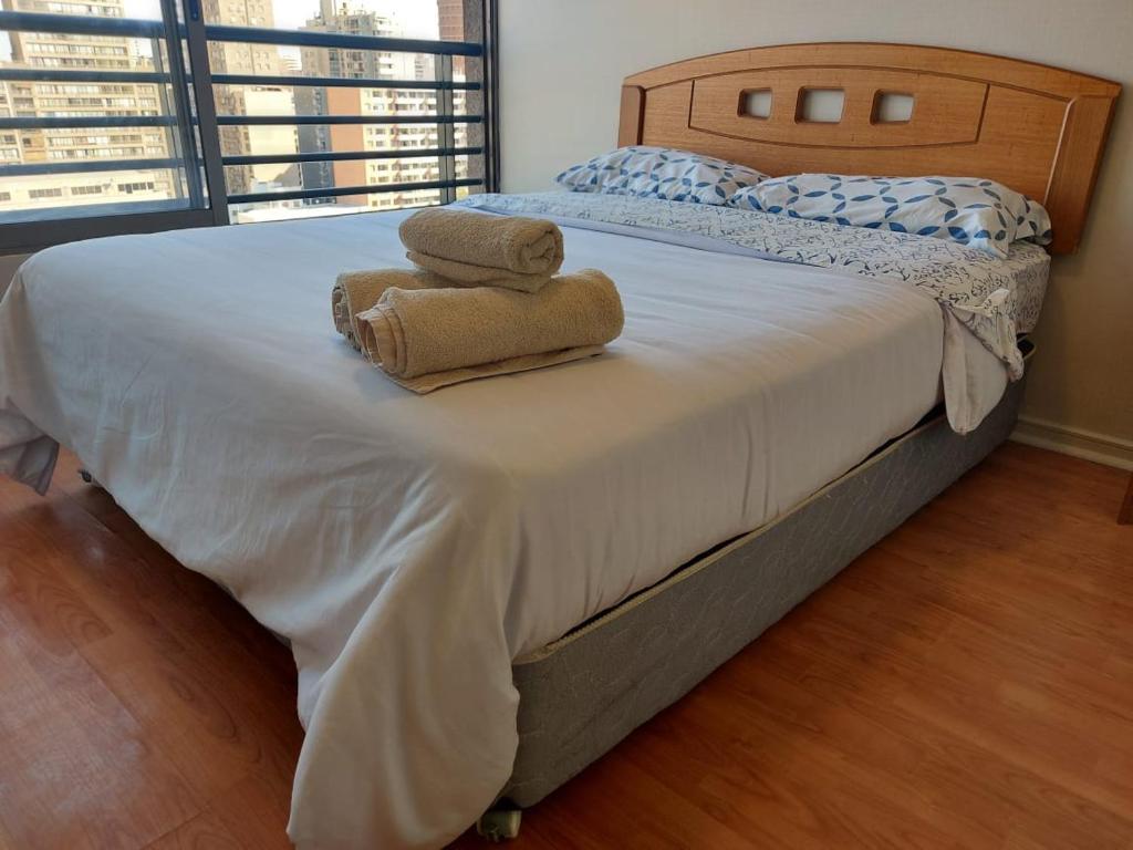 a bedroom with a bed with two towels on it at Departamento Metro Parque Bustamante in Santiago
