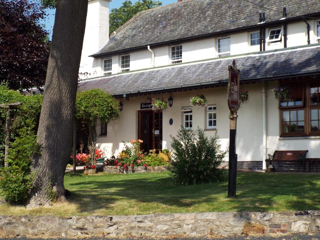 a white house with a tree in front of it at The Inn At Charlestown in Dunfermline