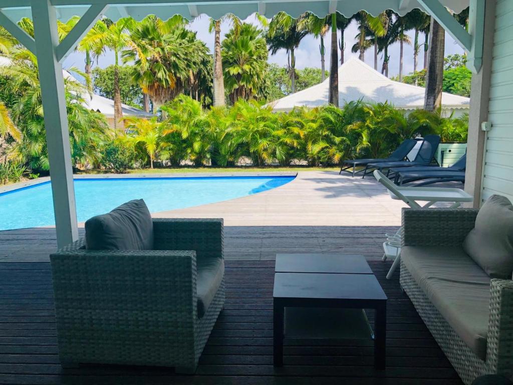 a patio with couches and a pool with palm trees at Villa Laurencin in Sainte-Rose