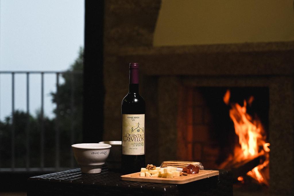 a bottle of wine and a plate of food next to a fireplace at Quinta De Calvelos in Vieira do Minho