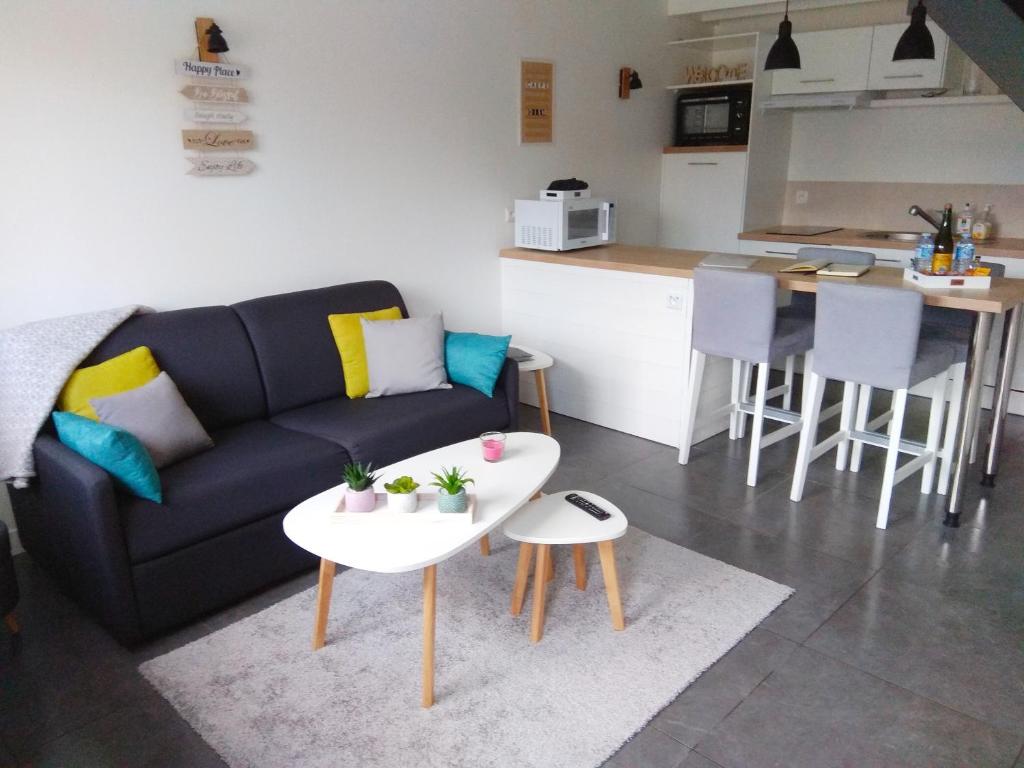 uma sala de estar com um sofá e uma mesa em Maison Cosy entre CAP FREHEL et SAINT MALO 1km PLAGE 5min GR34 Wifi Jardin Vélos "CASA OHANA" em Saint-Cast-le-Guildo