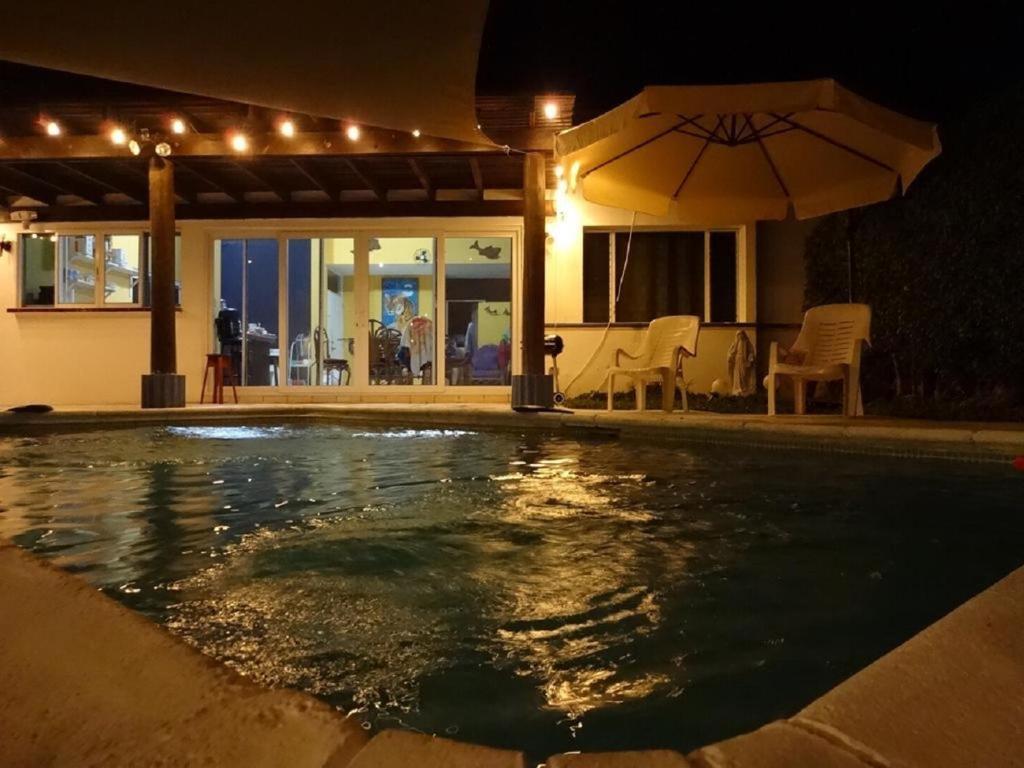 Chulamar的住宿－Puerto San José, Casa 33 Condominio Alta Mar，夜间游泳池,带遮阳伞