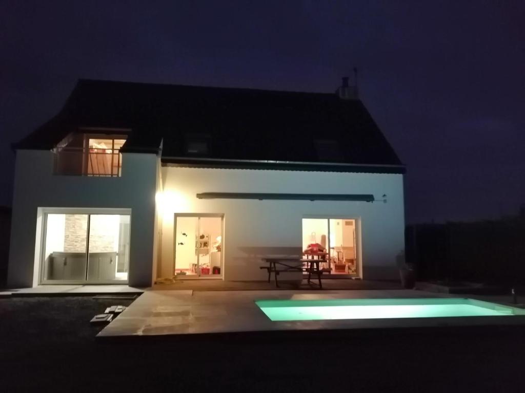 ein nachts beleuchtetes Haus mit Pool in der Unterkunft Villa bord de mer avec piscine et jacuzzi in Pénestin