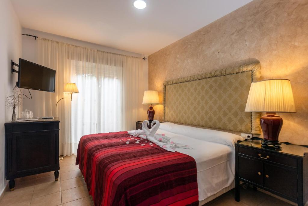 a hotel room with a bed with a red blanket at Hostal Alhaja Playa in El Puerto de Santa María