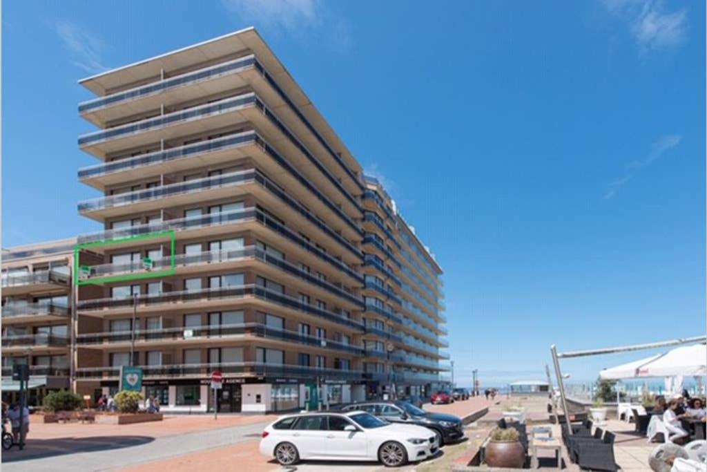 a large apartment building with cars parked in front of it at Casa Quatre-Mains Westende in Middelkerke
