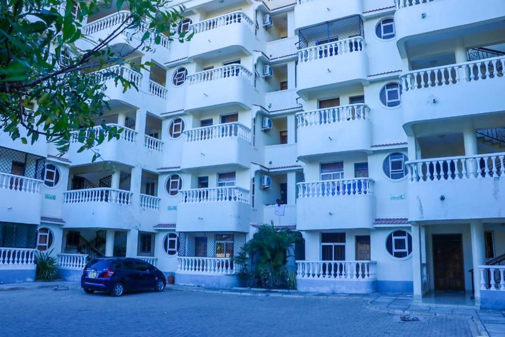 een wit gebouw met balkons en een auto aan de voorkant bij PK Ocean A3 in Mombasa