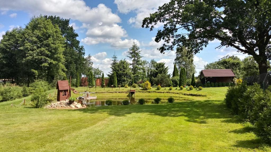 a garden with a pond in the middle of a field at Agroturystyka - Wypoczynek nad stawem na Kaszubach in Karsin