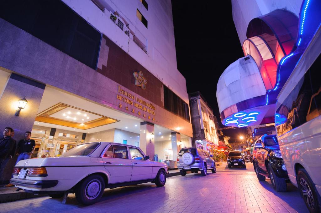 Betong Merlin Hotel في بيتونغ: سيارة بيضاء متوقفة في شارع المدينة ليلا