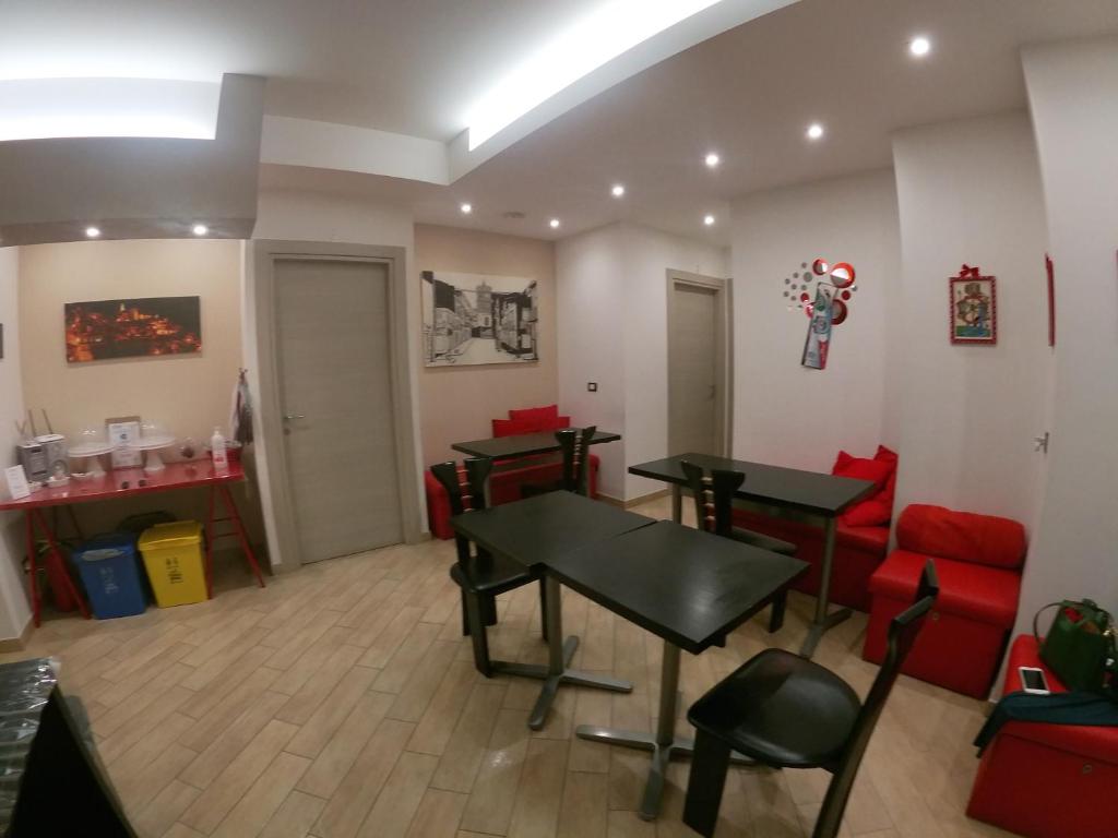 uma sala de espera com duas mesas e cadeiras vermelhas em B&B A Due Passi em San Giovanni Gemini