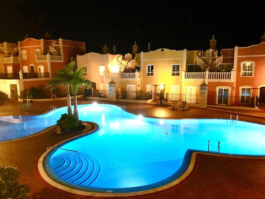 una gran piscina frente a un edificio por la noche en Elegant Palm Mar Apartment, en Palm-mar