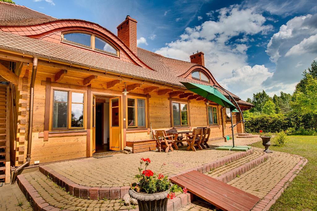 uma casa de madeira com um banco e um guarda-chuva em Dębowa Dziupla em Białowieża