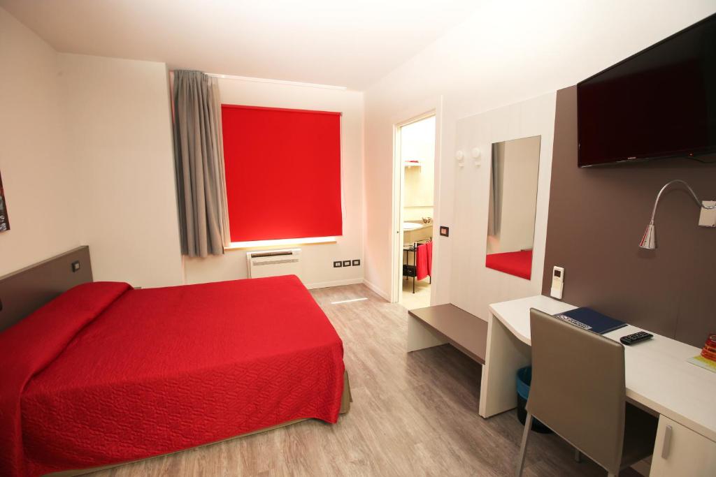 Habitación de hotel con cama roja y escritorio. en Ai Santi B&B en Dossobuono