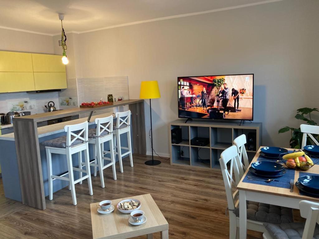 a living room with a kitchen and a tv on the wall at Dom na Folwarku POKOJE I APARTAMENTY, BEZPŁATNY ZAMYKANY PARKING NA TERENIE POSESJI in Kielce