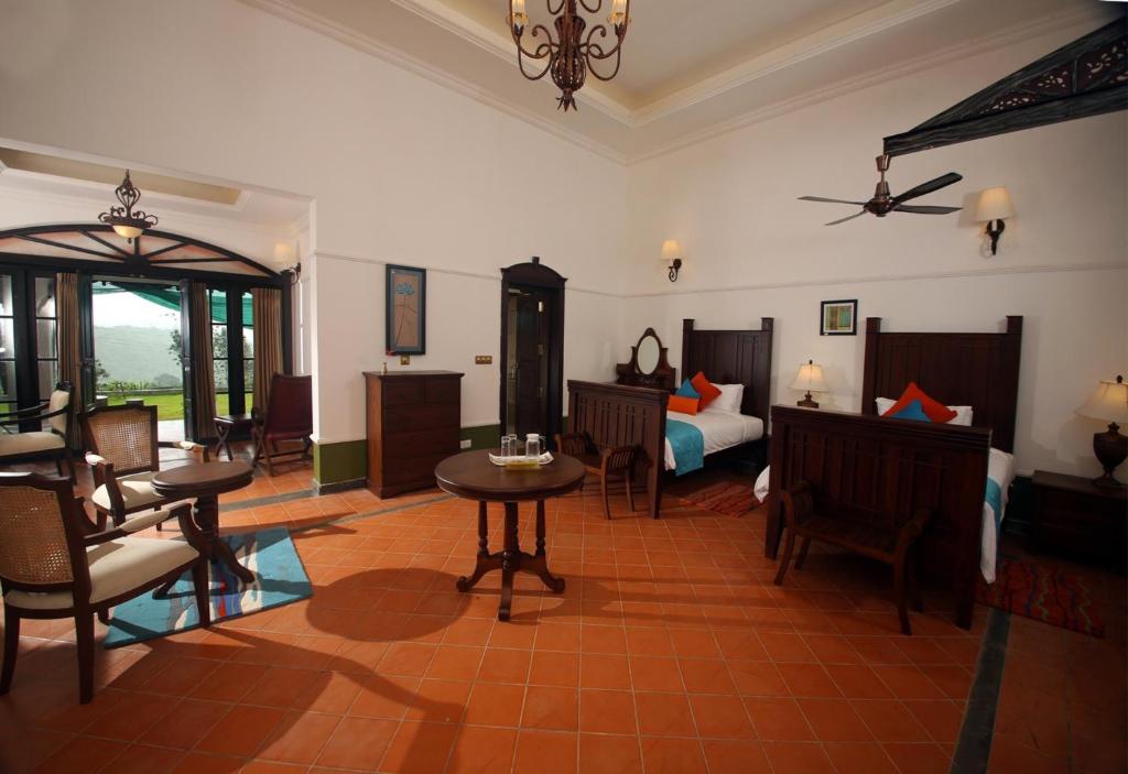 a room with a bed and a table and chairs at Parisons Plantation Experiences by Abad in Mananthavady