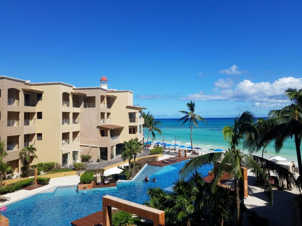 a view of a resort with a swimming pool and the ocean at Ocean Front El Faro Reef 304 in Playa del Carmen