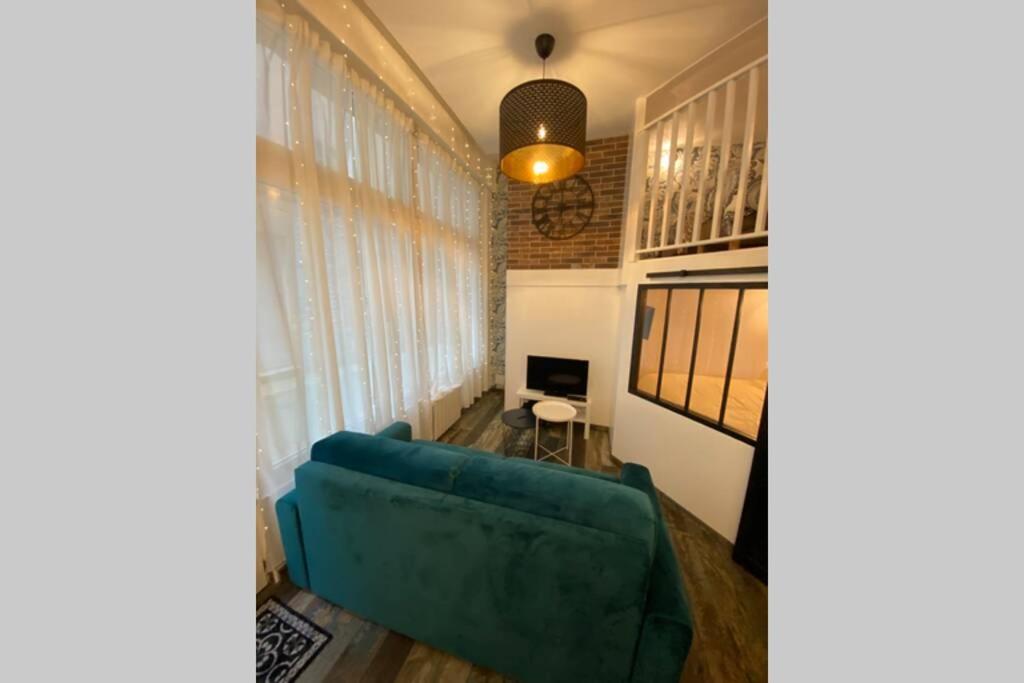 a living room with a blue couch in a room with windows at Le Plongeoir de Bon-Secours in Saint Malo