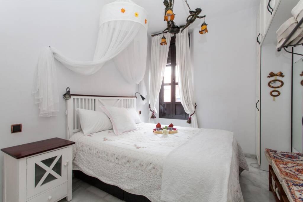 1 dormitorio con 1 cama con colcha blanca y ventana en Apartamento Alfarería en Sevilla