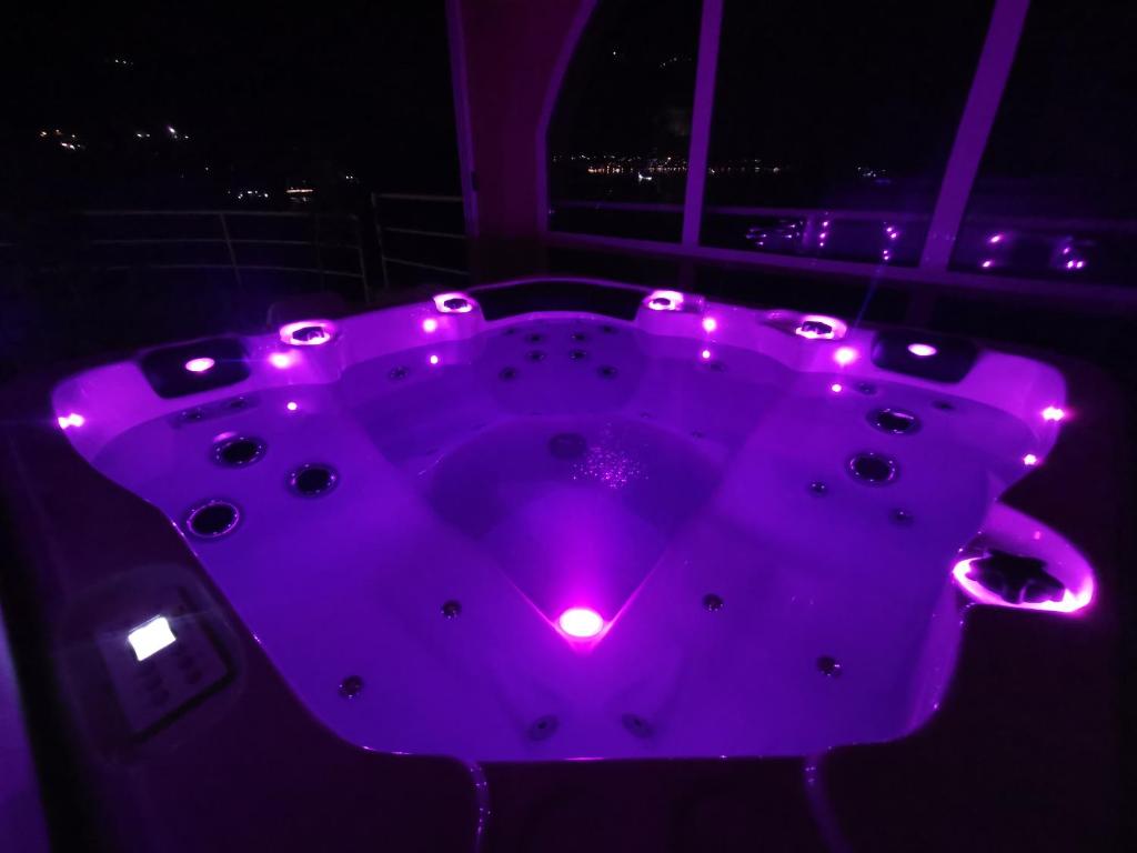 una bañera púrpura con luces en la oscuridad en Holiday Apartment Lira jacuzzi - sea view- terrace en Mlini