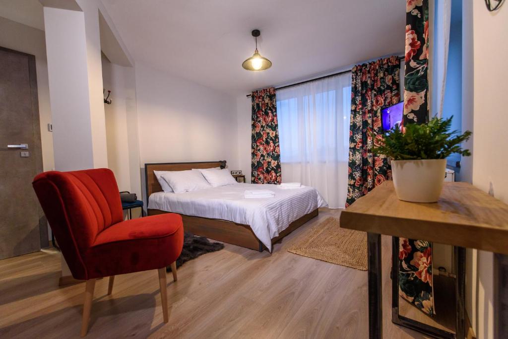 um quarto com uma cama e uma cadeira vermelha em TamTam Urban em Cluj-Napoca