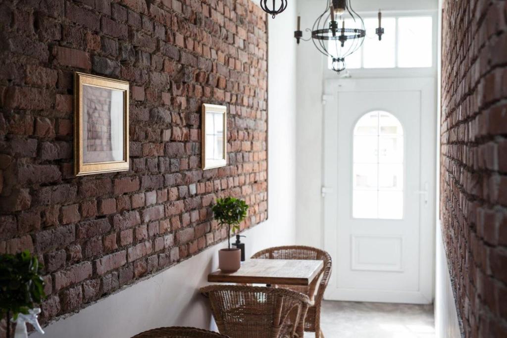 Cette chambre dispose d'un mur en briques, d'une table et de chaises. dans l'établissement Boleslav Home De Luxe, à Sucha Beskidzka