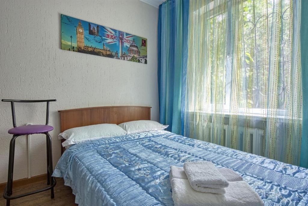 a bedroom with a bed and a window with blue curtains at Апартаменты на улице Клочкова, 128 in Almaty