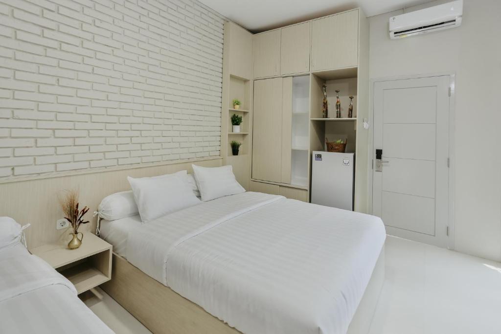 a white bedroom with two beds and a brick wall at House of Asiyah Syariah in Solo