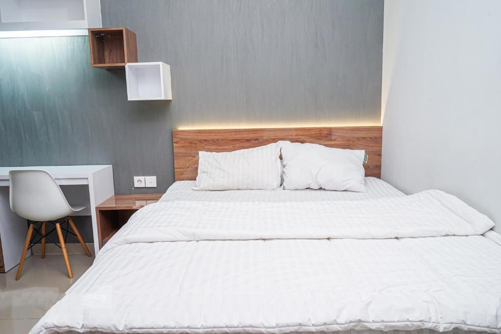 a bedroom with a large white bed and a desk at Apartemen Taman Melati Yogyakarta by ArFe Room in Yogyakarta