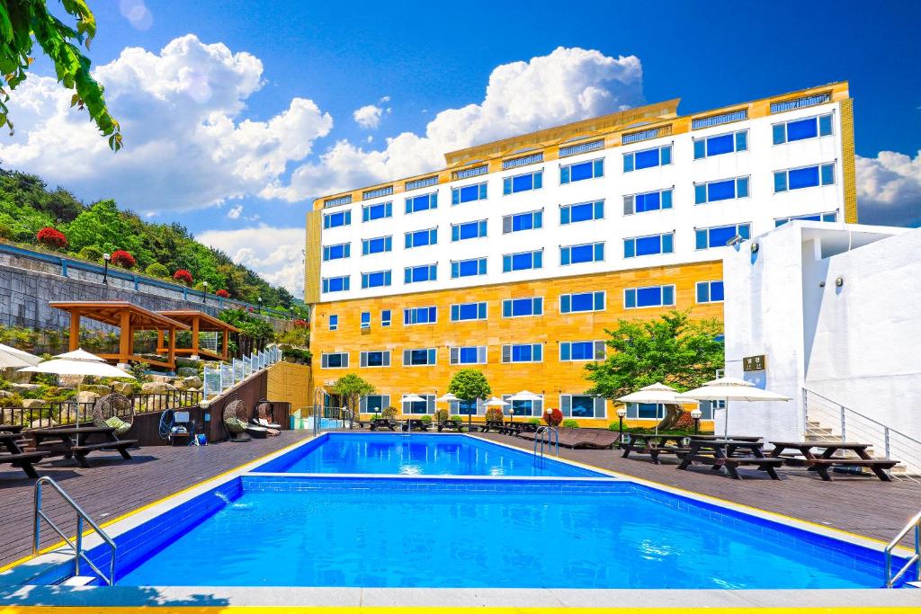 a hotel with a swimming pool in front of a building at Doya Hotel Geoje in Geoje 