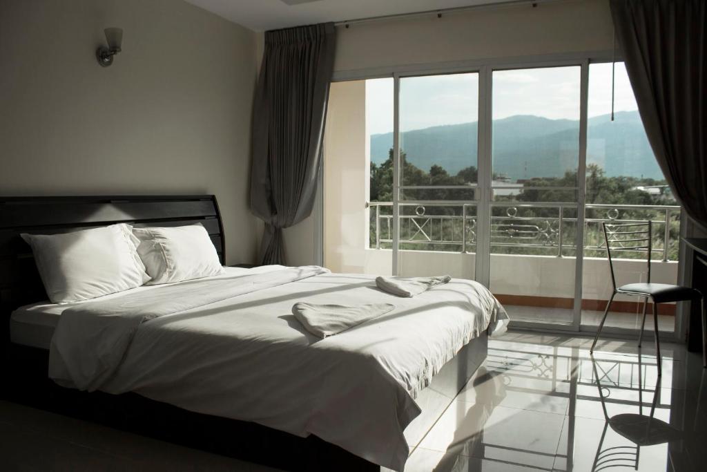 a bedroom with a bed and a large window at Nattidaplace Hotel Chiangmai in Chiang Mai