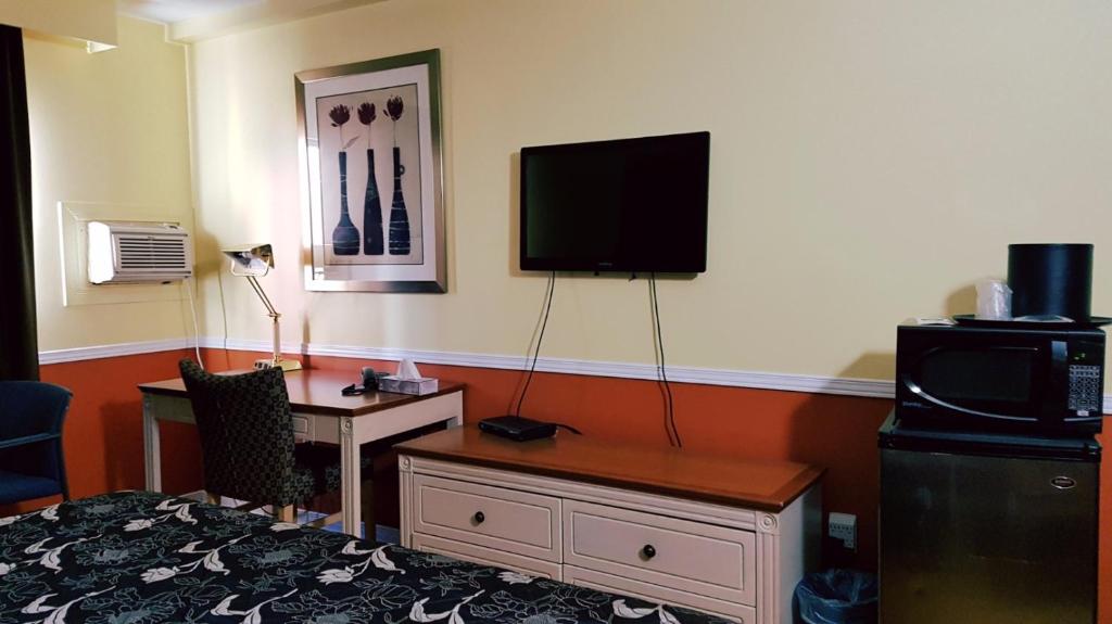 a hotel room with a desk and a tv on the wall at Budget inn 2000 in Hamilton