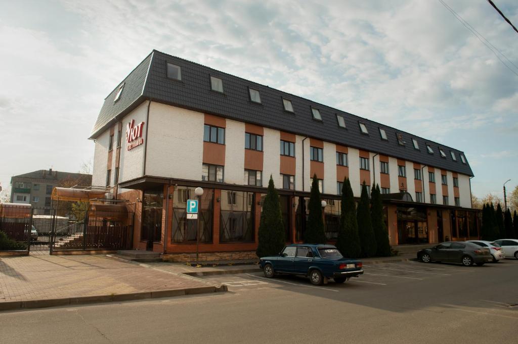 a building with a car parked in a parking lot at Uyut Centralnaya Hotel in Klintsy