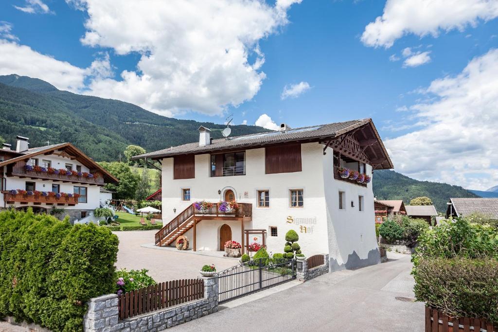 une maison dans un village avec des montagnes en arrière-plan dans l'établissement Sigmundhof, à Bressanone