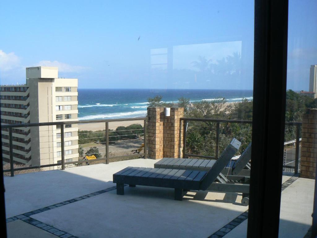 a bench on a balcony with a view of the ocean at The Don Lodge in Amanzimtoti