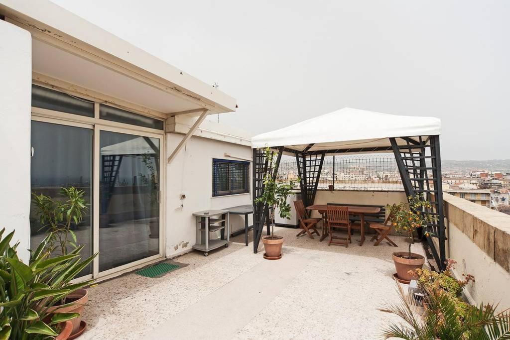 uma varanda de uma casa com uma mesa e um guarda-chuva branco em One bedroom appartement at Catania 200 m away from the beach with furnished terrace and wifi em Catânia