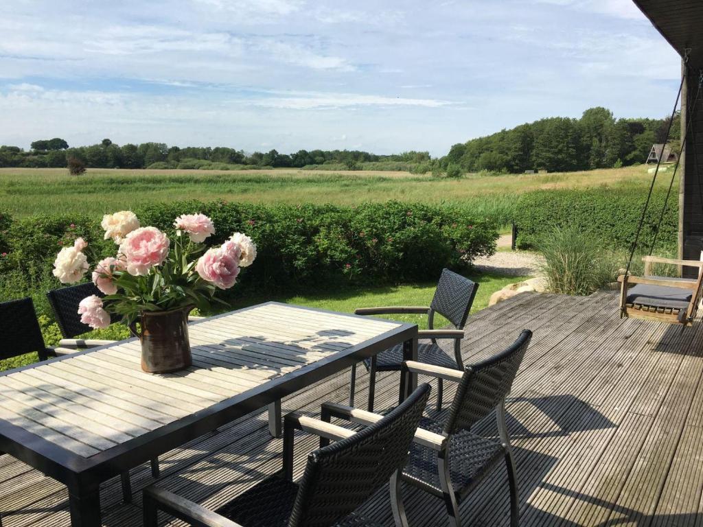 a wooden table with a vase of flowers on a deck at Schöne Aussicht in Brodersby
