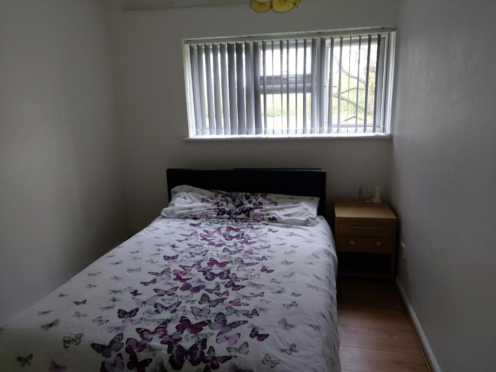 a bedroom with a bed with a floral comforter and a window at Relaxing double bedroom in Romford