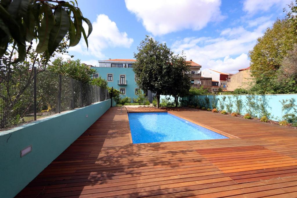 een achtertuin met een zwembad en een houten terras bij HM - Segredo do Porto in Porto