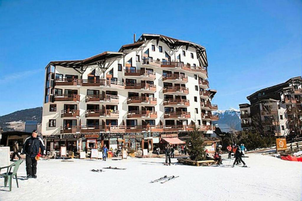 a large building with people walking around in the snow at Residence Le Christiana - maeva Home in La Tania